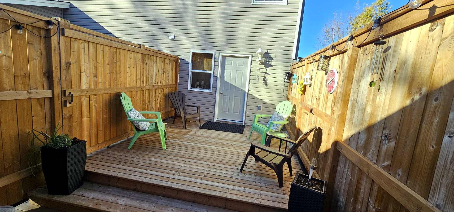 Wooden terrace by the house with green and brown lounge chairs